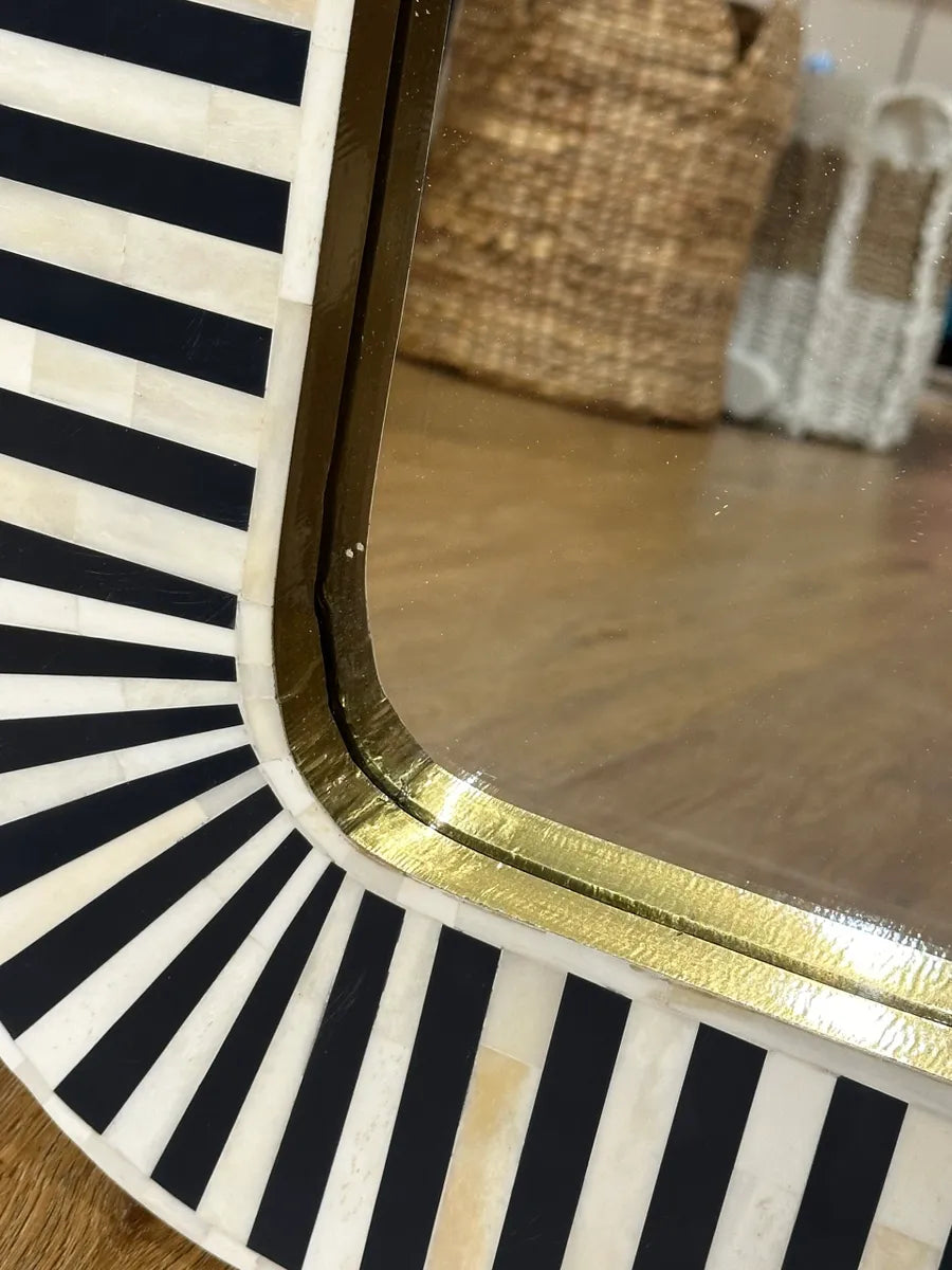 Round mirror with black and white striped border and gold trim