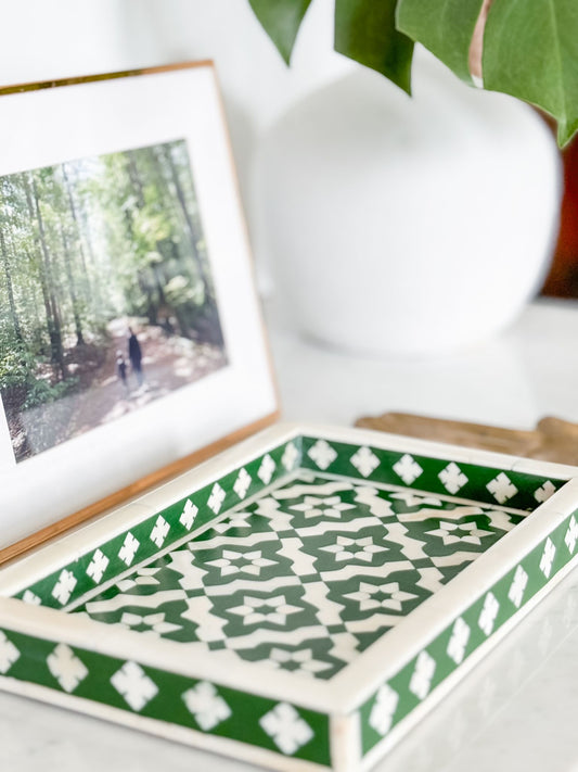 Decorative box with green and white pattern next to a framed photo of a forest scene.