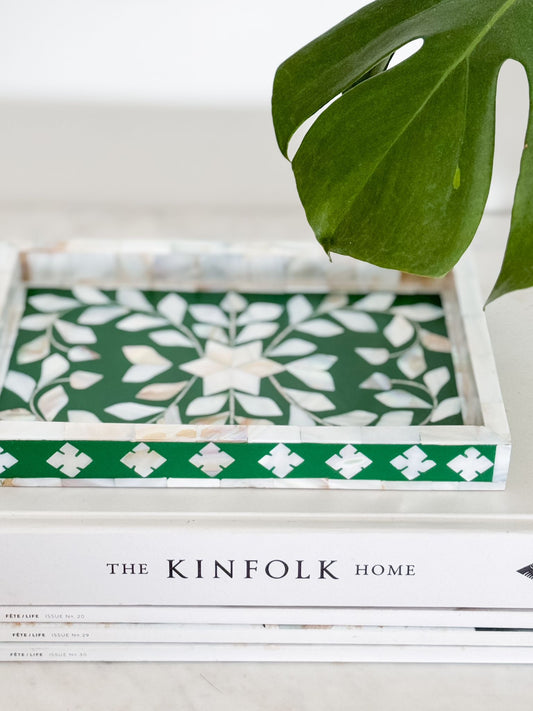 Decorative tray with green and white pattern on a surface with 'The Kinfolk Home' magazine.