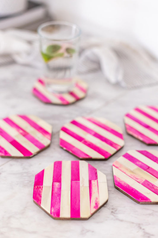 Hexagonal coasters with pink and white striped design on a marble surface