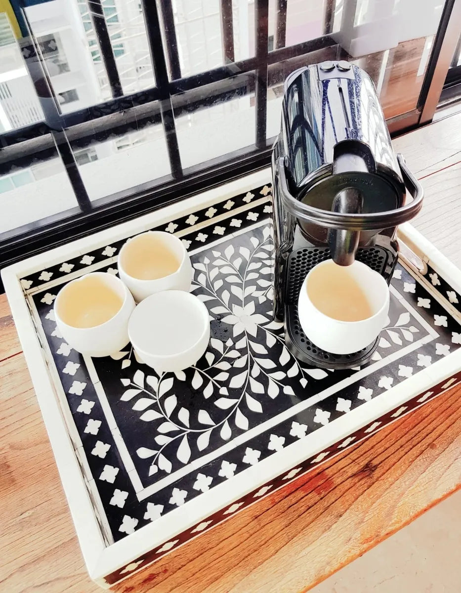 white cups on a decorative tray with a coffee machine in the background.