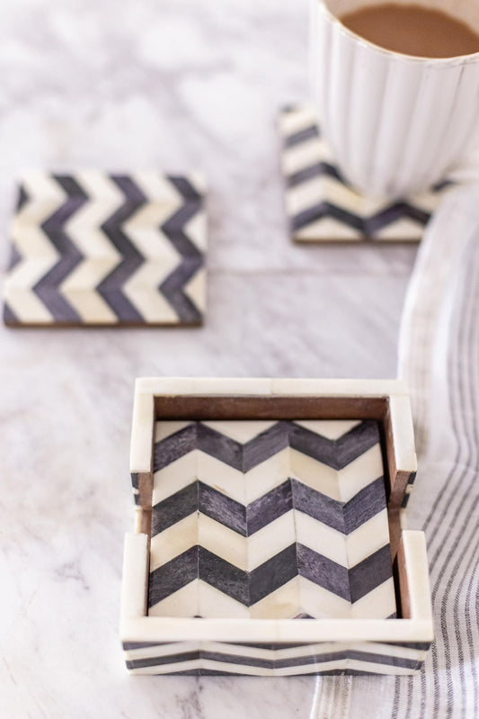 Chevron patterned coasters on a marble surface with a cup of coffee.
