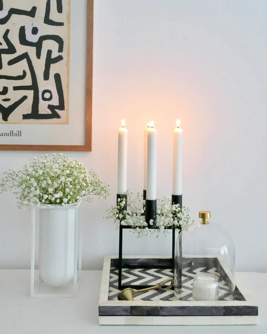 Decorative setup with candles, flowers, and a tray on a table.