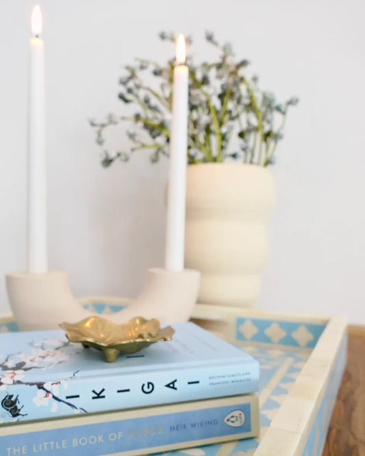 Stack of books with candles and a decorative bowl on a table