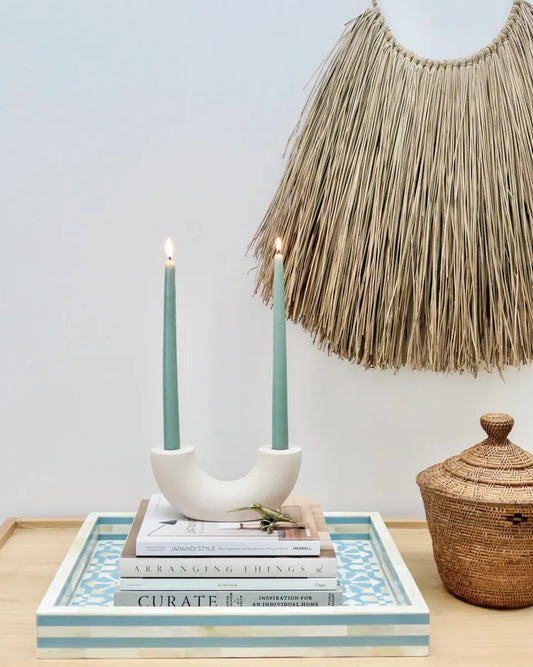 Decorative setup with candles, books, and a woven basket on a tray.