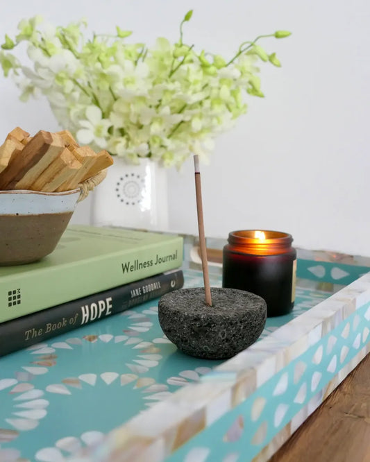 Decorative tray with books, candle, and flowers on a light background