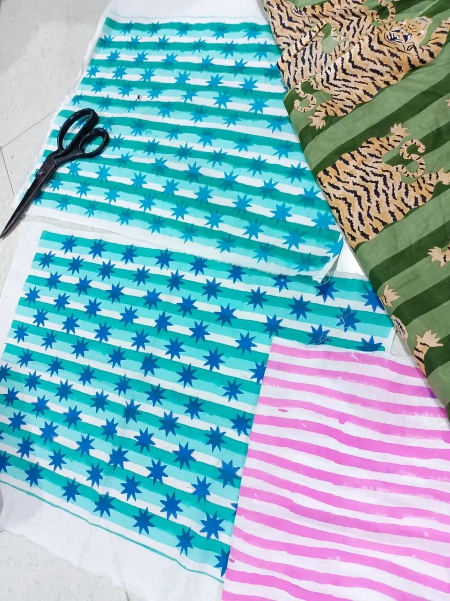 Fabric with blue and white striped pattern, green and gold patterned fabric, and pink and white striped fabric on a white background.