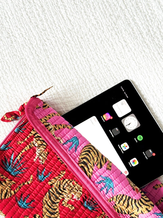 Pink pouch with tiger pattern next to a smartphone on a white surface