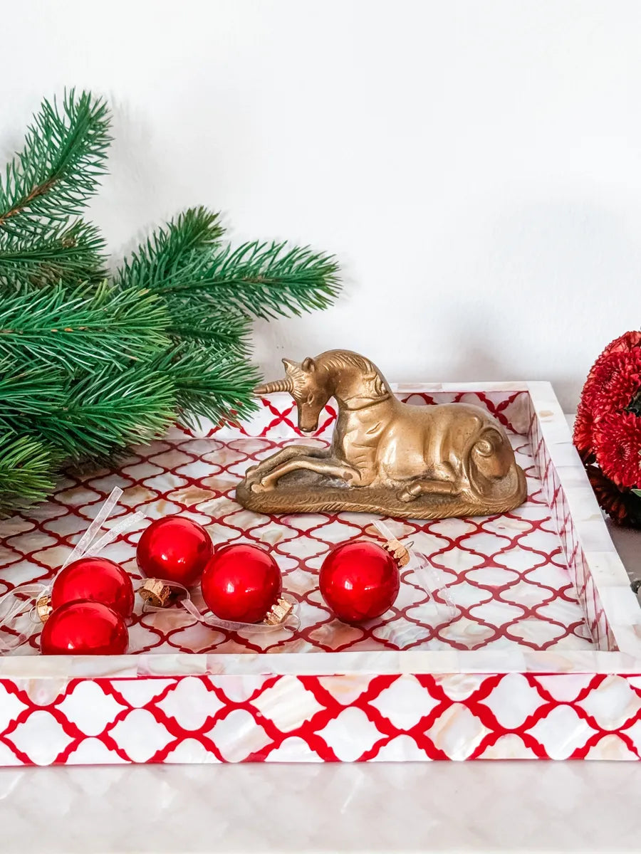Decorative tray with gold unicorn, red ornaments, and Christmas tree branches on a white background