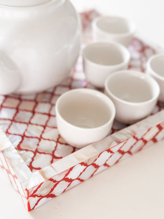 Set of white ceramic cups on a decorative tray with a red and white pattern