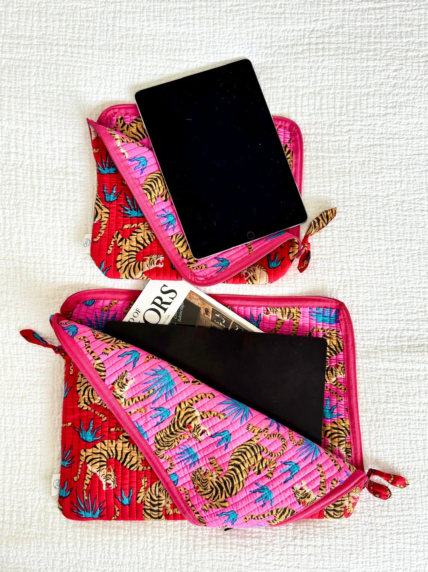 Pink pouch with tiger pattern containing a tablet and magazine on a white background