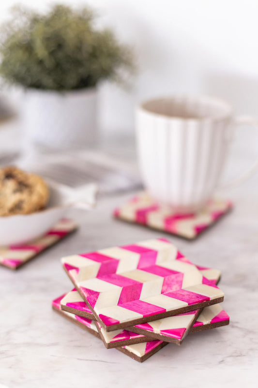 Stack of pink and white chevron coasters on a light surface with a blurred background