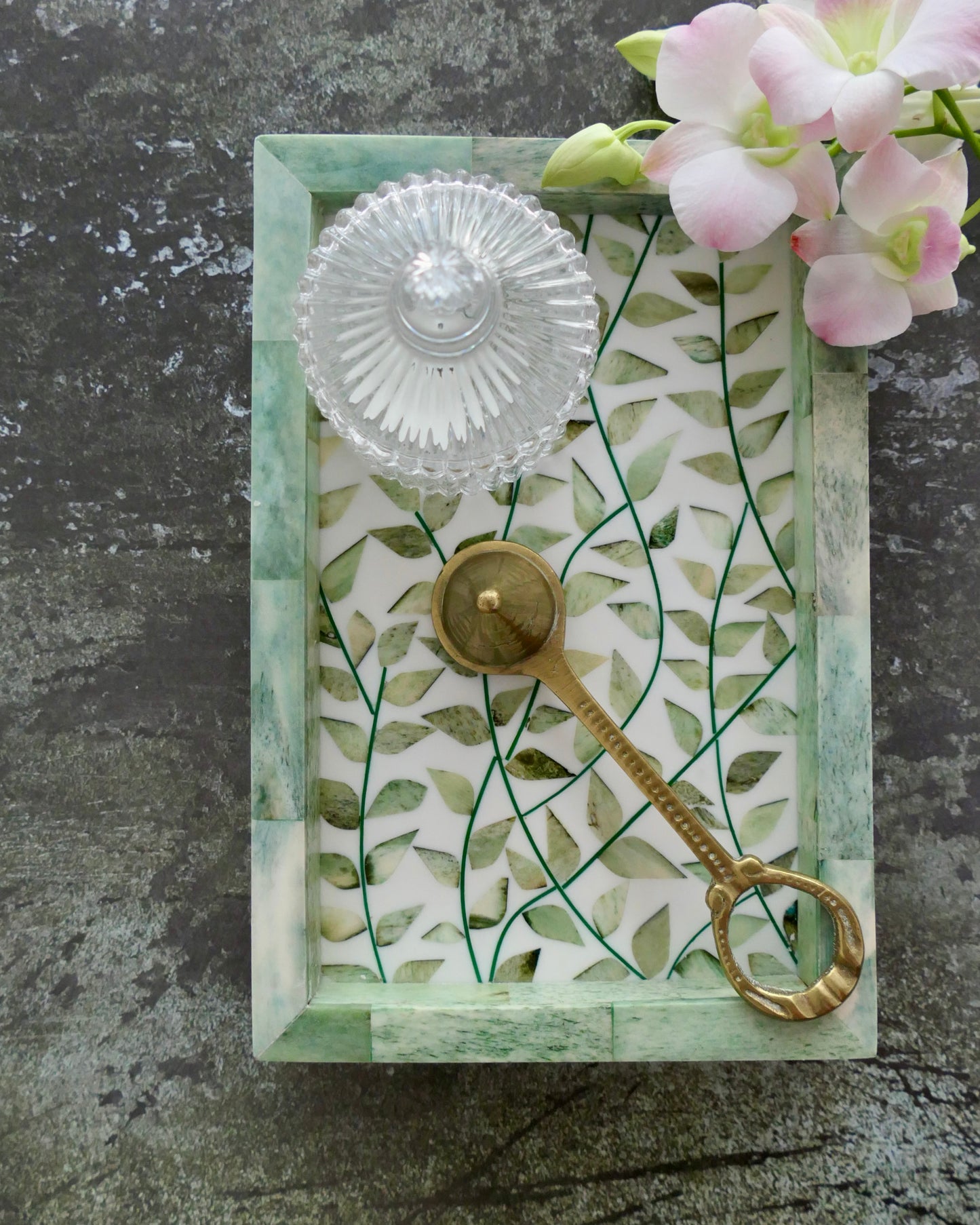 Decorative key with a glass knob on a leaf-patterned card against a gray background