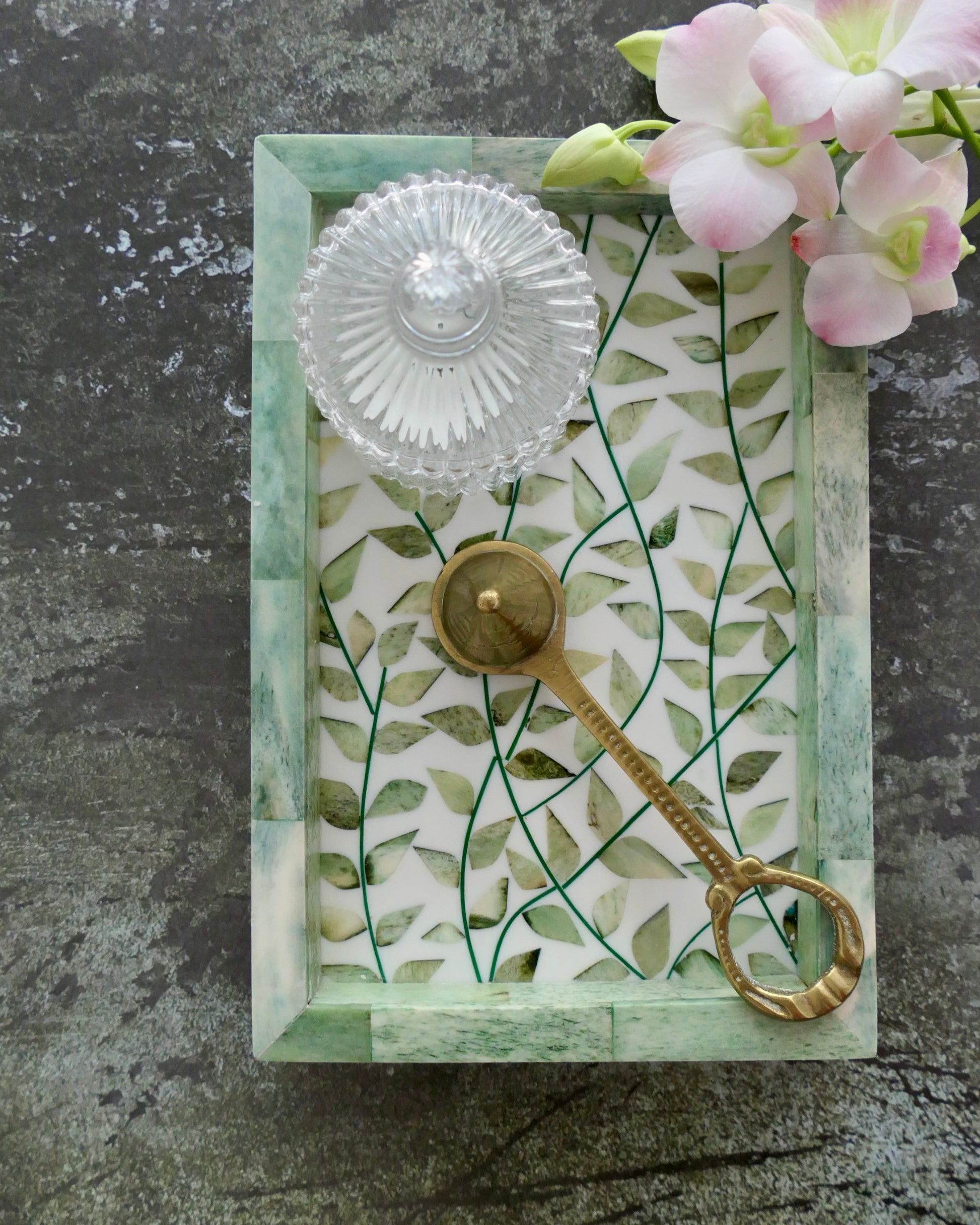 Decorative key with a glass knob on a leaf-patterned card against a gray background