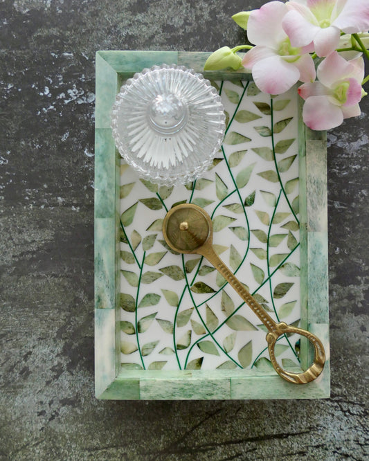 Decorative key with a glass knob on a leaf-patterned card against a gray background