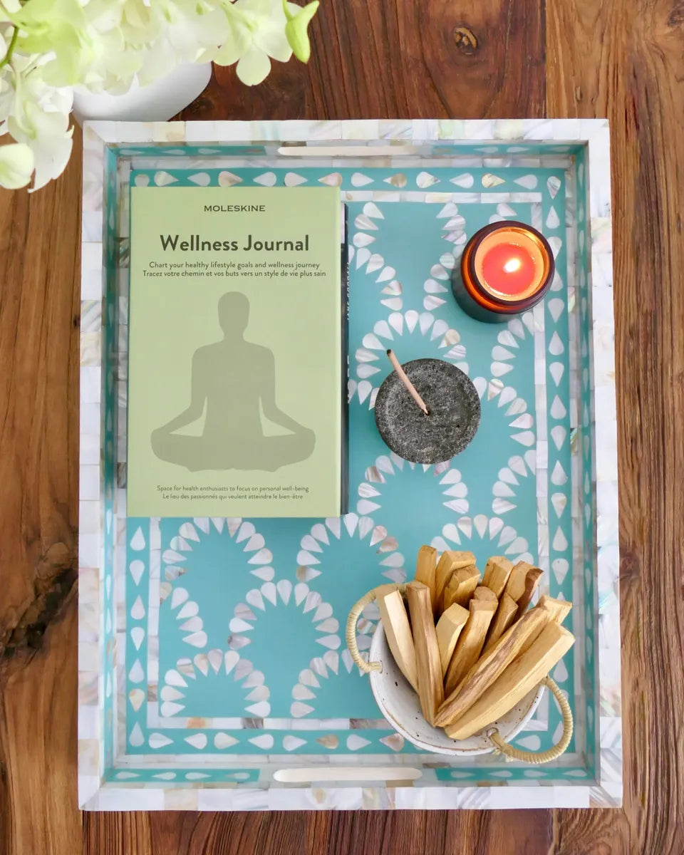 Wellness journal with candles and incense on a decorative tray