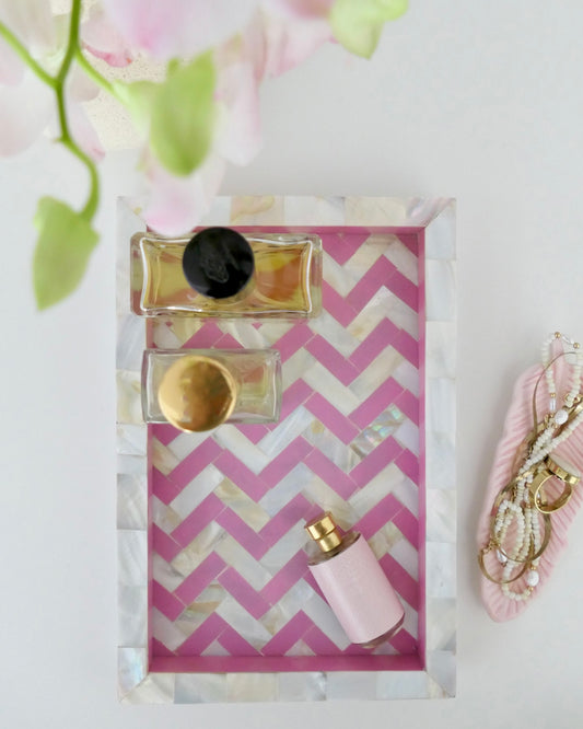 Set of perfume bottles on a pink and white zigzag patterned card with floral background