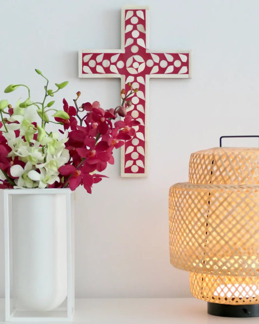 Decorative cross, flowers, and lamp on a white surface with a light background