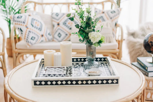 Round coffee table with decorative tray, candles, and flowers in a living room setting.