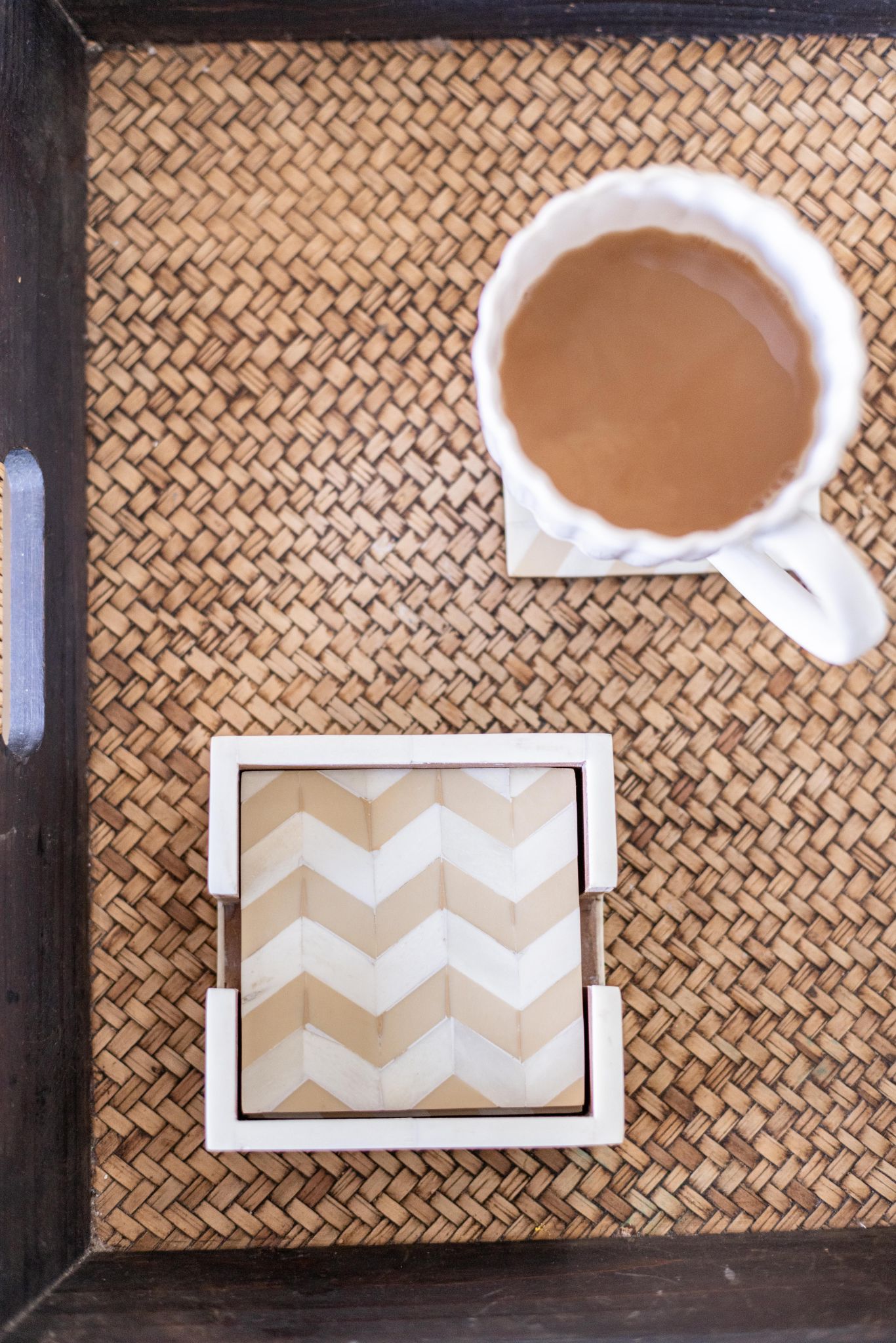 Chevron-patterned coaster on a woven surface with a cup of coffee.