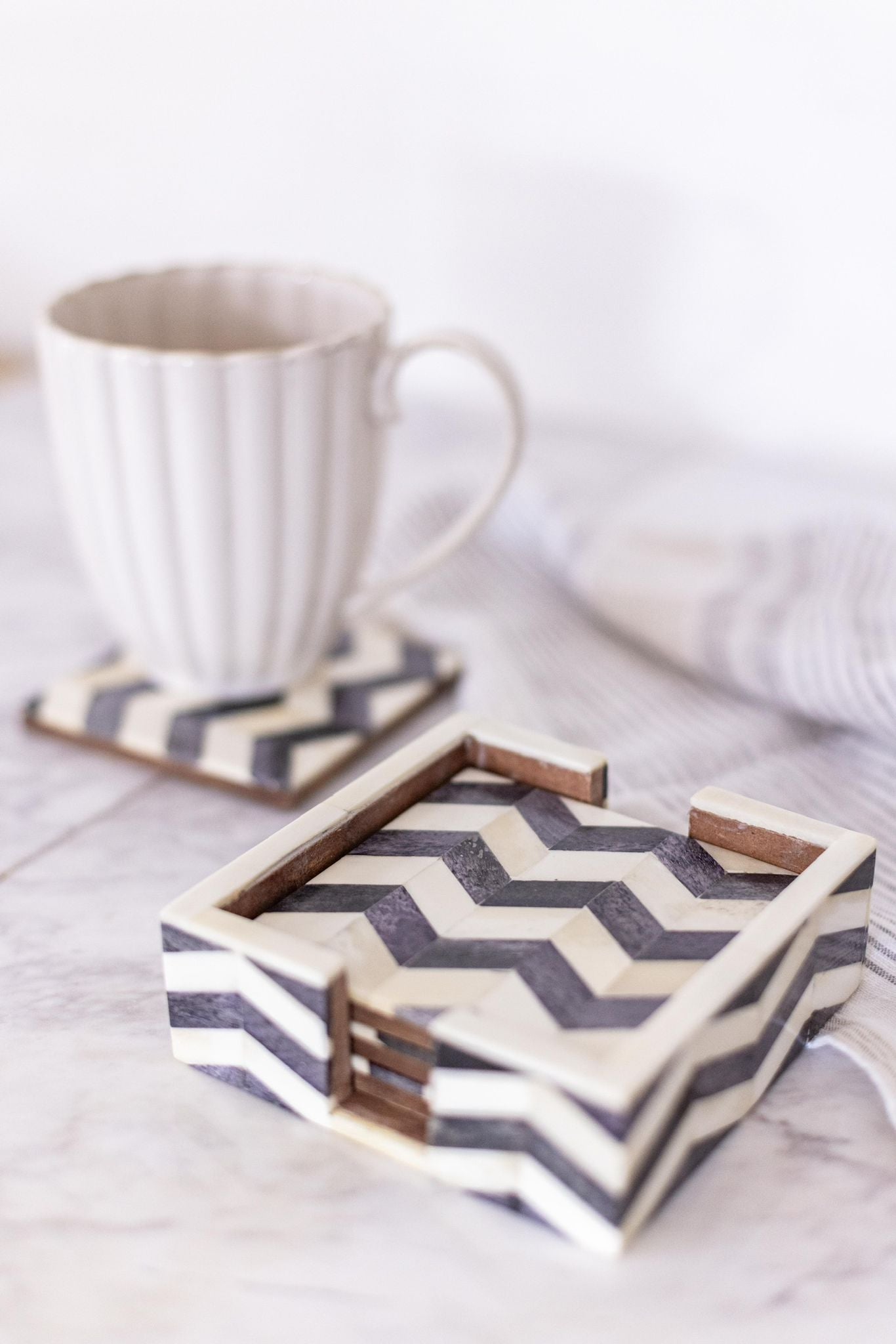 Chevron patterned coaster set with a mug on a light surface