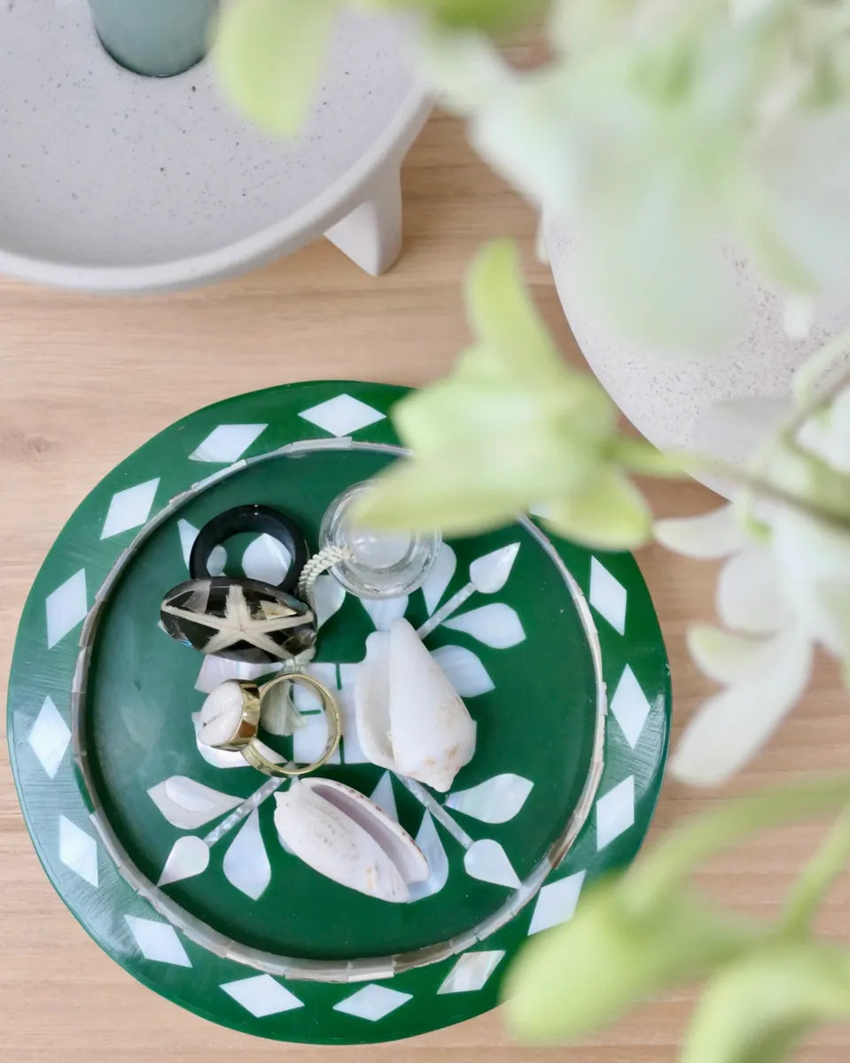 Green jewelry holder with rings on a wooden surface