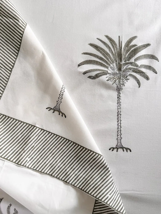 White fabric with black palm tree designs and stripes on a white background