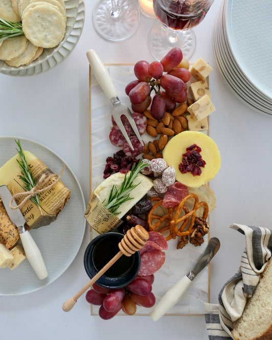 Assorted food platter with cheeses, fruits, and meats on a white table.
