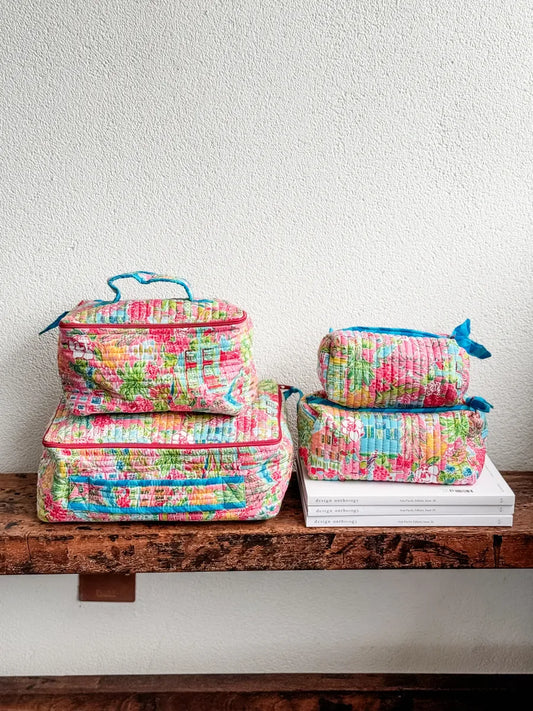 Set of colorful floral-patterned packing cubes on a wooden surface with a white wall background.