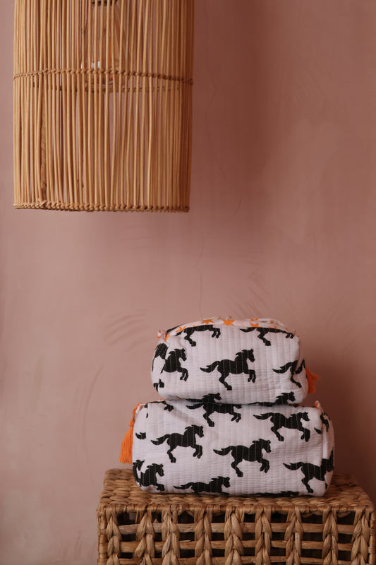 Two patterned cushions on a pink surface with a woven basket and wooden blind.