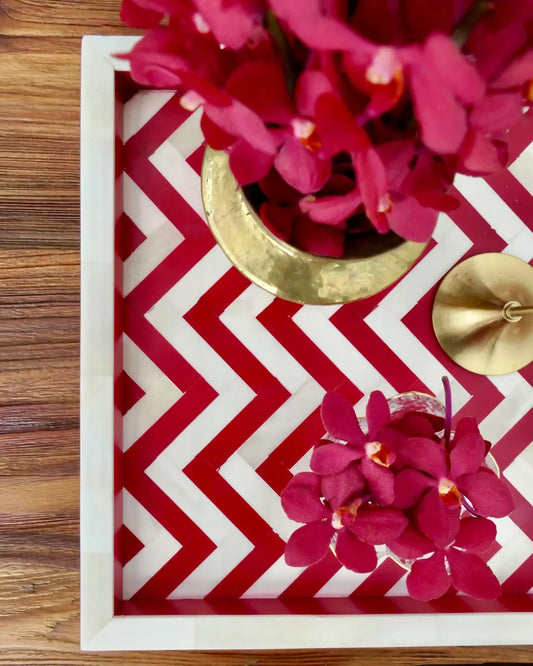 Decorative tray with red and white chevron pattern and pink flowers on a wooden surface