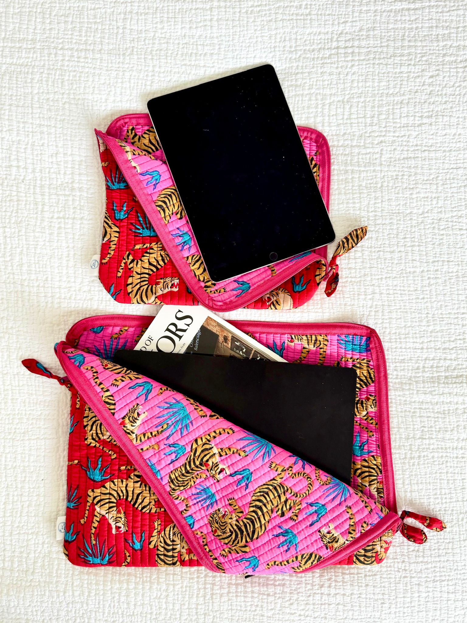 Pink pouch with tiger pattern containing a tablet and magazine on a white background