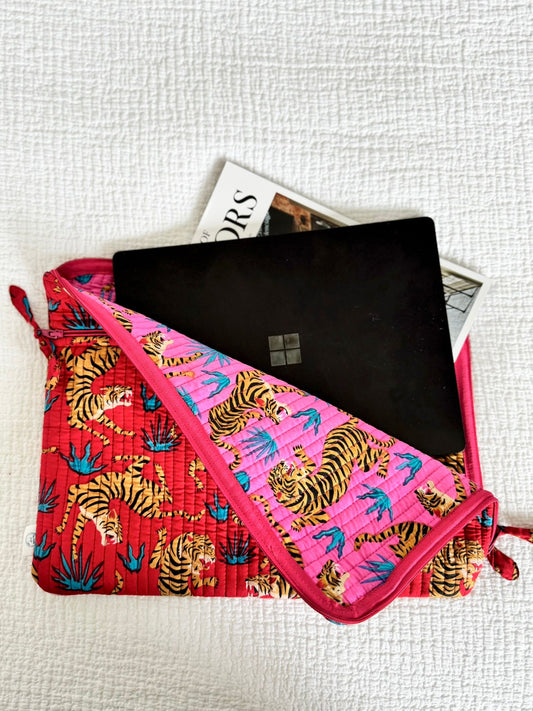 Pink pouch with tiger pattern containing a black laptop on a light gray background